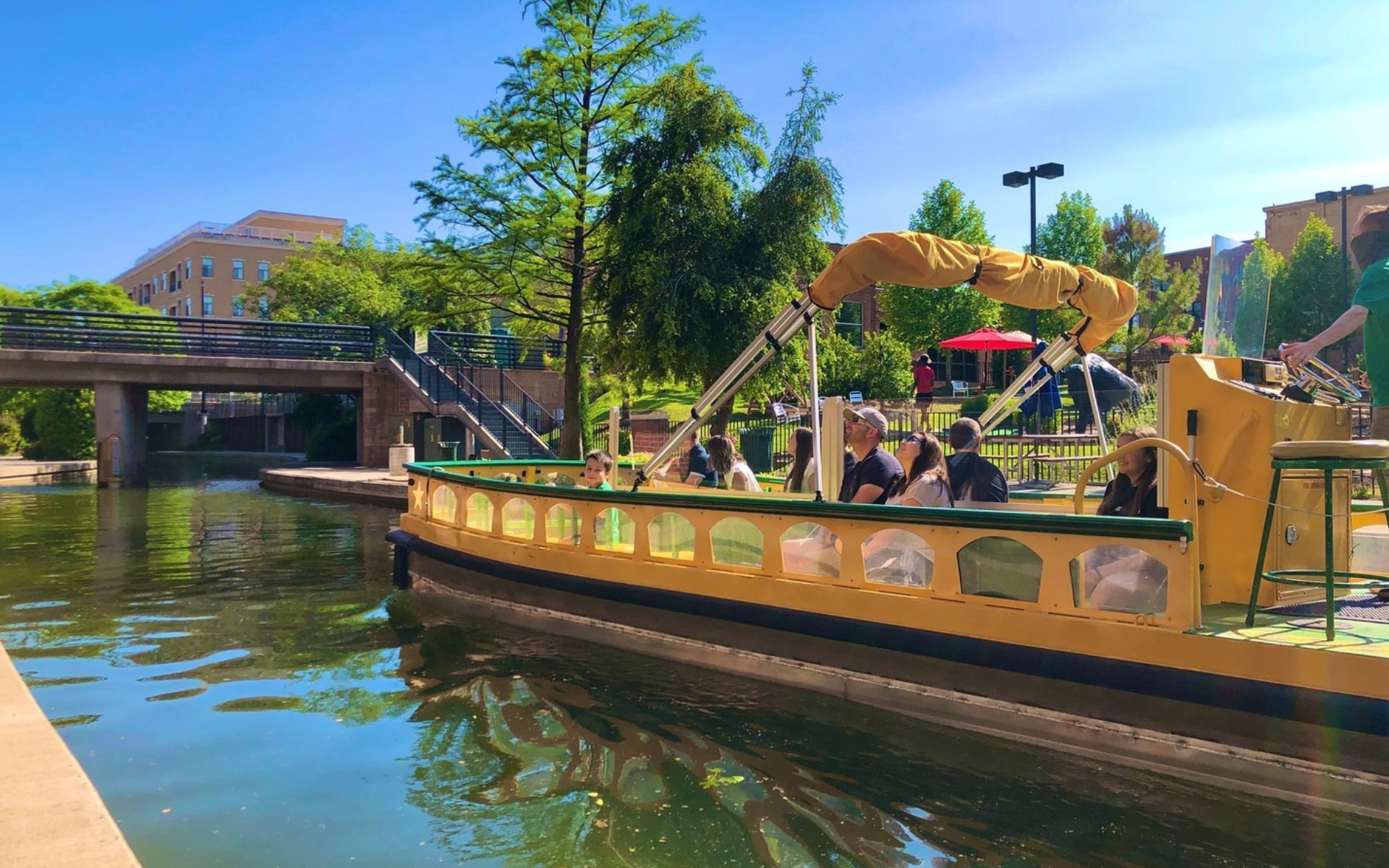 A yellow boat full of people floating down a man-made river in the heart of Oklahoma City.